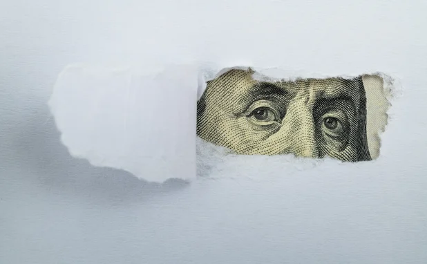 Torn white paper revealing US Currency - stock photo