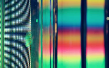 Close-up of a colorful LED display with vibrant pixel patterns and blurred neon light reflections—a visual concept of technology and data