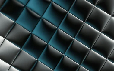 Abstract geometric background featuring a repeating pattern of metallic black, silver and teal-blue triangular shapes with reflective lighting, creating a three-dimensional, faceted surface for modern technology, digital innovation and corporate design themes