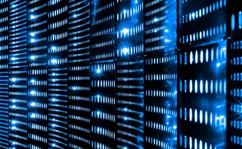 Close-up view of glowing blue LED lights on data server racks in a dark data center, representing cloud computing, cybersecurity, and digital infrastructure