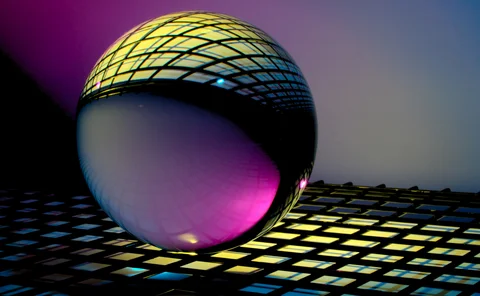 Futuristic orb reflecting a dark lattice illuminated with vibrant pink, yellow, and blue lighting.