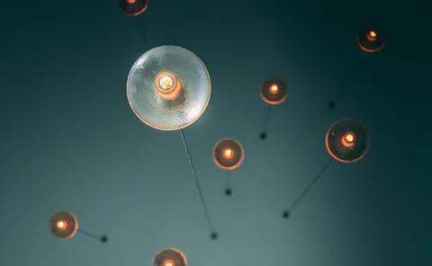 Modern cluster of glass globe pendant lights with exposed filament bulbs providing warm ambient lighting in a high-ceiling room