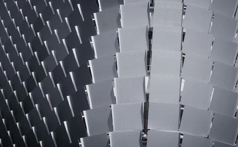 Abstract architectural pattern of repeating rectangular panels in alternating light and dark grey tones, creating a geometric 3D effect.