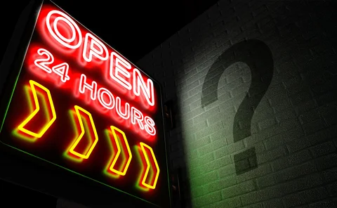 “Open 24 hours” neon sign with a shadowy question mark on the adjacent wall