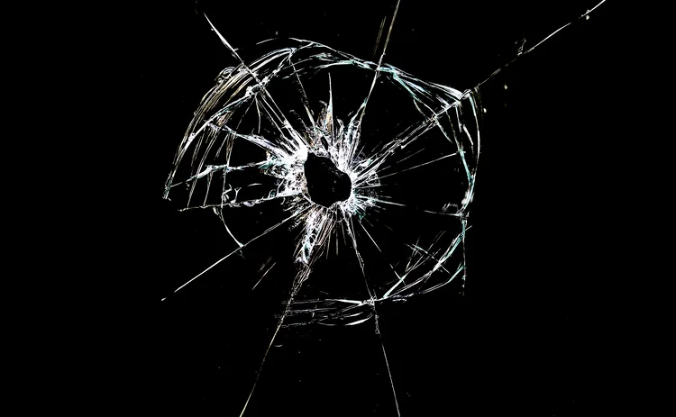 hole with cracks in the glass isolated on a black background
