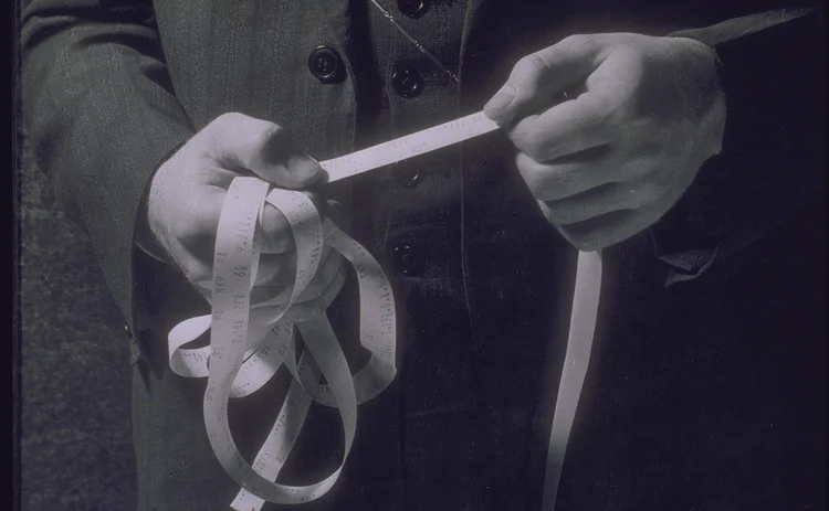 Man holding ticker tape showing stock prices