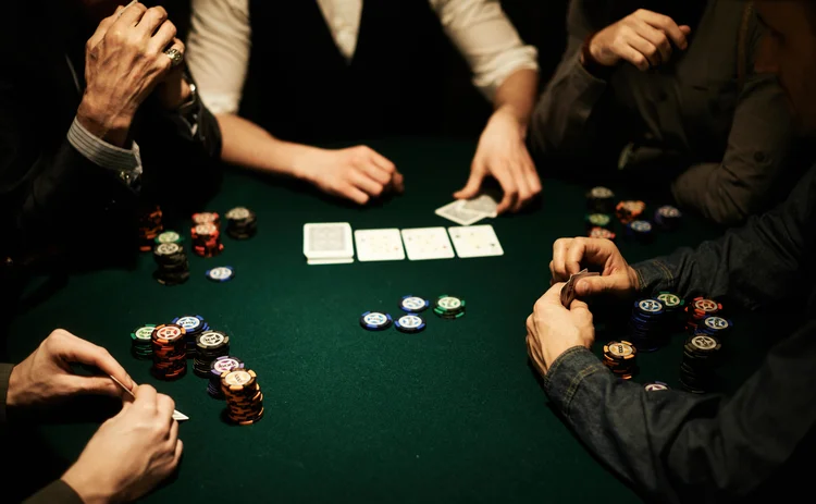 Players' hands, stacks of gambling chips and cards on poker table