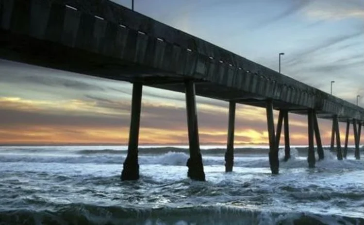 california-pier-silhouette-stretching-out-into-dark-sea-at-sunset