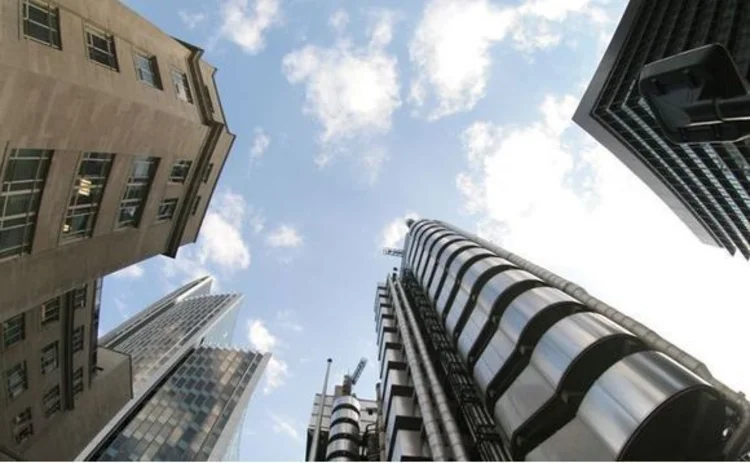 looking up into the clouds between buildings in the City of London