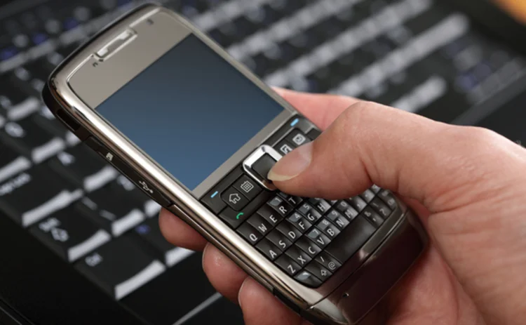 Person operating a mobile phone and laptop Person operating a mobile phone and laptop