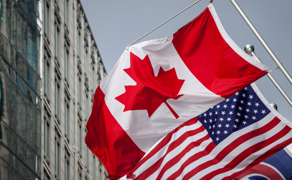 Picture of the canadian flag joint with and american stars and stripes flag taken in front of a cold and blue business building in the CDB of Toronto. Toronto is the biggest city of Canada, and a major hub for economy, politics and business in America.