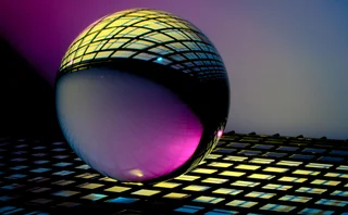 Futuristic orb reflecting a dark lattice illuminated with vibrant pink, yellow, and blue lighting.