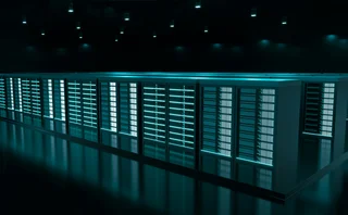 Modern data centre with rows of illuminated server racks in a dark room, showcasing high-performance computing infrastructure and cloud storage technology.