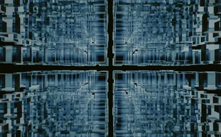 Abstract digital structure of translucent blue cubes forming a symmetrical grid-like tunnel with a glowing cross shape at the center, evoking themes of data architecture, AI systems, and virtual environments.