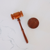 A wooden gavel on a white marble backdrop