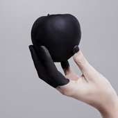 Studio shot of a woman's hand holding a black apple